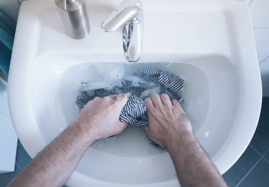 在水槽中手洗条纹衬衫的人顶视图图片