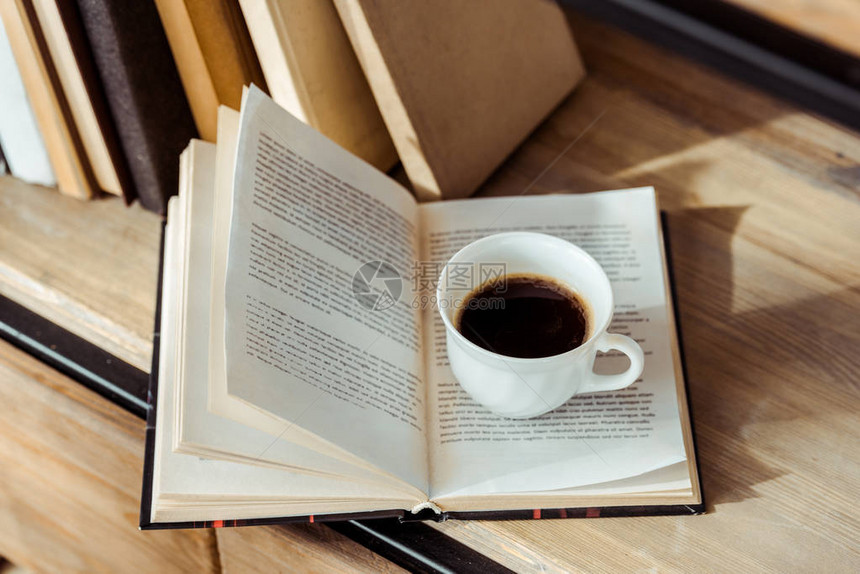 书架上放着一杯咖啡的打开书的特写图片