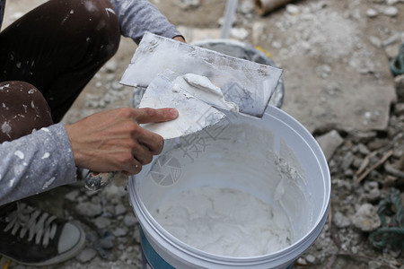 石膏工在桶中混合石膏用于翻新装修图片