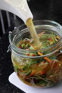 把肉汤倒在罐子里的盆栽蔬菜面条上图片
