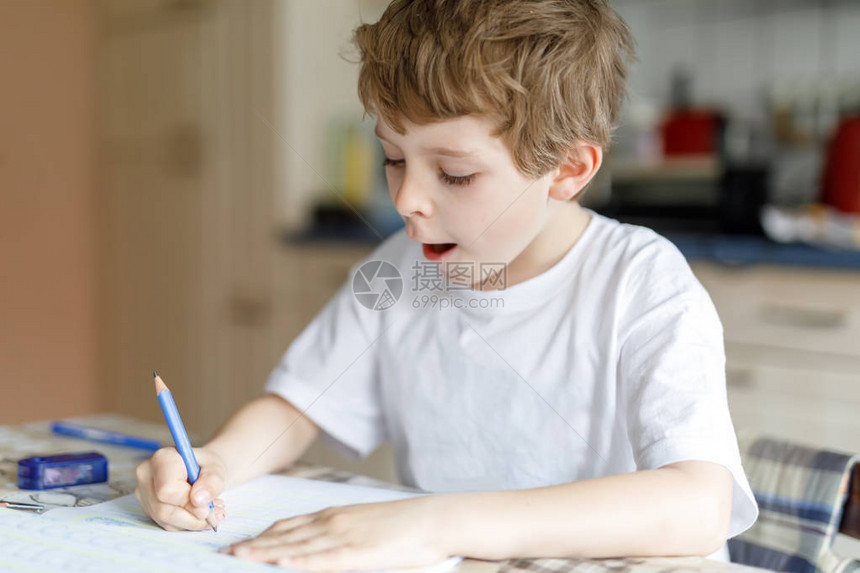 可爱的快乐学校孩子男孩在家做作业的画像小孩用彩色铅笔在室内写字小学和教育孩子学习图片