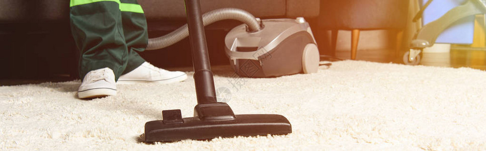 使用真空吸尘器和清洁白地毯的专业工图片