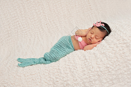 新出生的女婴穿着一副卷轴和珊瑚色美人鱼装扮图片