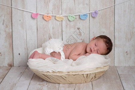 一个两周大的新生女婴睡在一个木碗里白色木质背景上有一个柔图片
