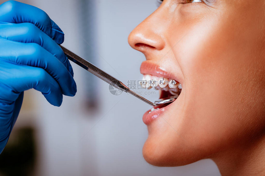 一名牙科医生检查牙套对年轻女病人用牙图片