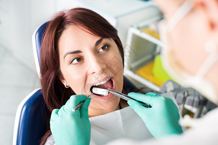 女牙医为患者做牙科治疗做准备她在病人嘴里插入化妆棉选择聚图片