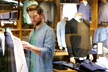 一位年轻男子在商店看衣服图片