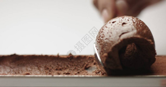 从一个不锈钢锅里取出的软海绵巧克力慕斯和一块孤立在图片