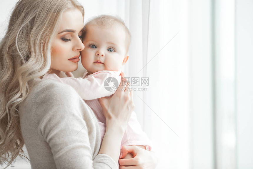 照顾她的小女婴的年轻母亲美丽的妈和她的女儿在卧室里充满爱的家庭有吸引力的妈图片