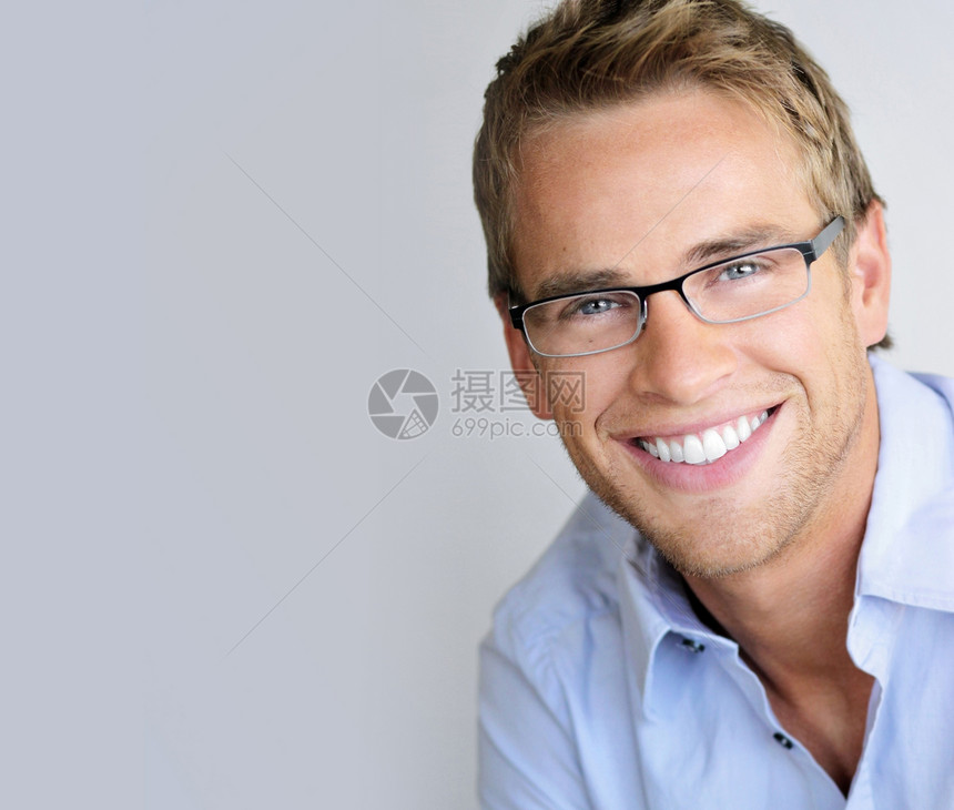 长着笑的英俊年轻男子戴着时装眼镜在中背景和大图片