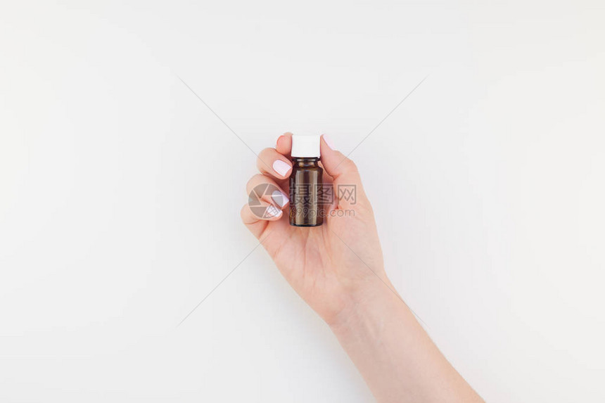 女人手与柔和的修指甲油拿着小玻璃瓶隔离白色背景与复制空间模拟天然油水疗医疗产品女图片