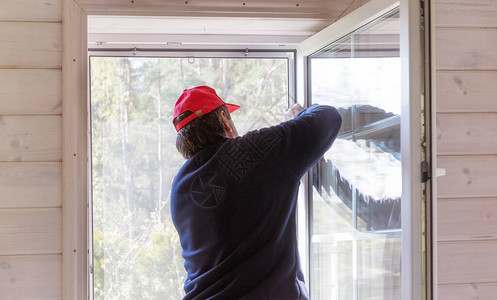 工人在木屋窗户上安装蚊子网或蚊子电线屏幕图片