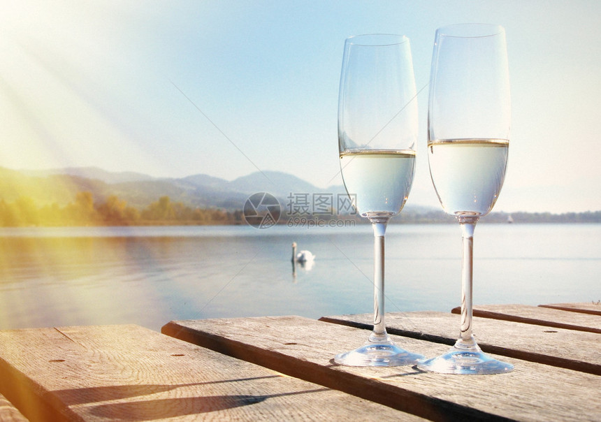 两个香槟杯靠在湖边图片