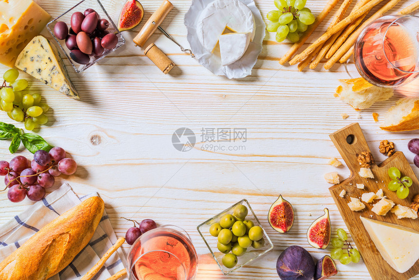 白色木制桌上有各种奶酪葡萄酒和零食图片