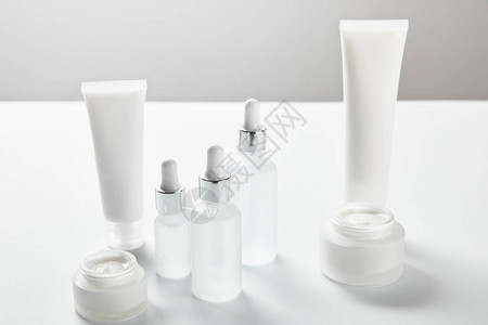 奶油管化妆品玻璃瓶和白涂背景图片