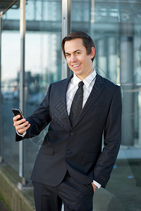 一个商人在户外用手机微笑的肖像图片