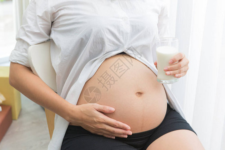 孕妇为保健而喝着一杯新鲜牛奶以图片