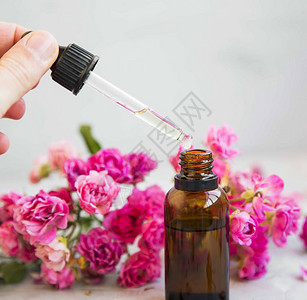 用于芳香疗法的玫瑰油瓶和带玫瑰花的水疗中心带滴管的水疗图片