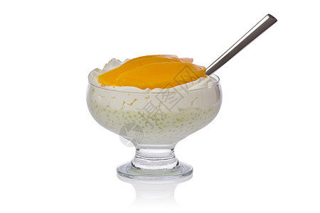 带奶油芒果片和勺子的塔皮欧卡布丁放在玻璃碗图片