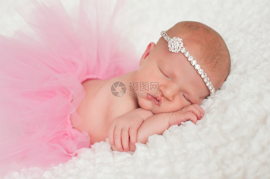 睡着8天大的新生女婴穿着粉红色的芭蕾舞短裙和水钻头带她趴着睡在一条白色图片