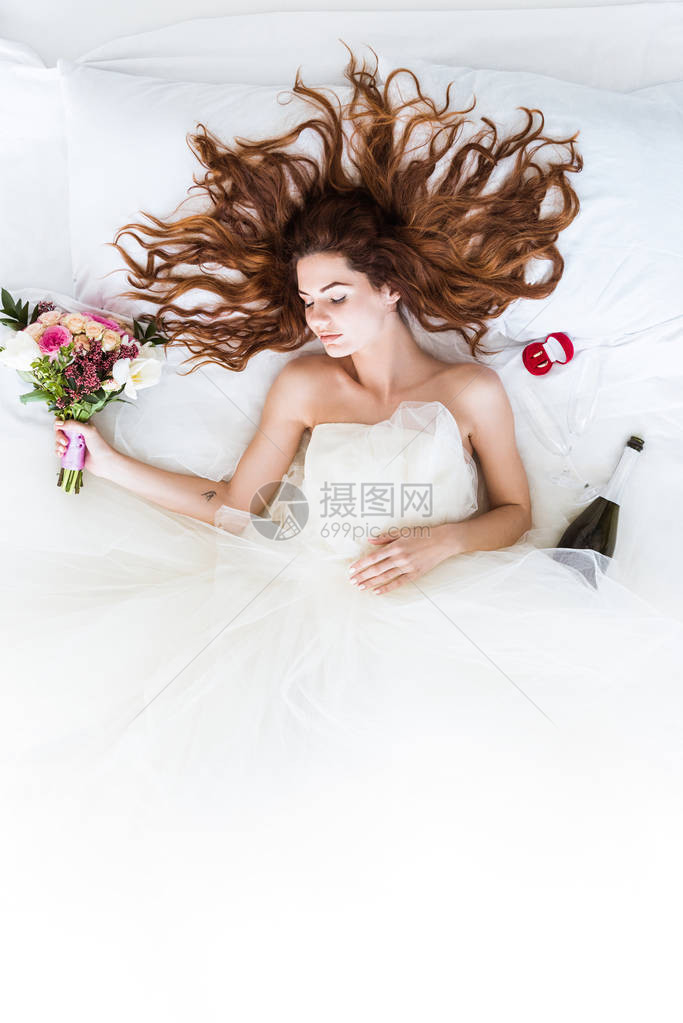 穿着婚纱的年轻女孩睡在有花和结婚戒指图片