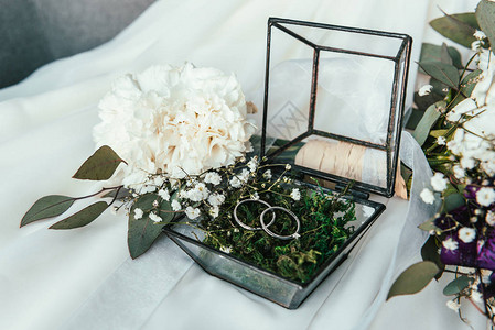白色的鲜花结婚戒指在生锈的盒子里图片