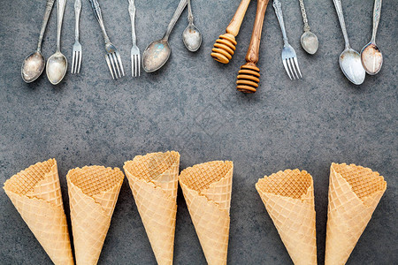 平面的冰淇淋锥勺子叉子和蜂蜜薄饼在暗石底背景上收集甜食菜单设图片