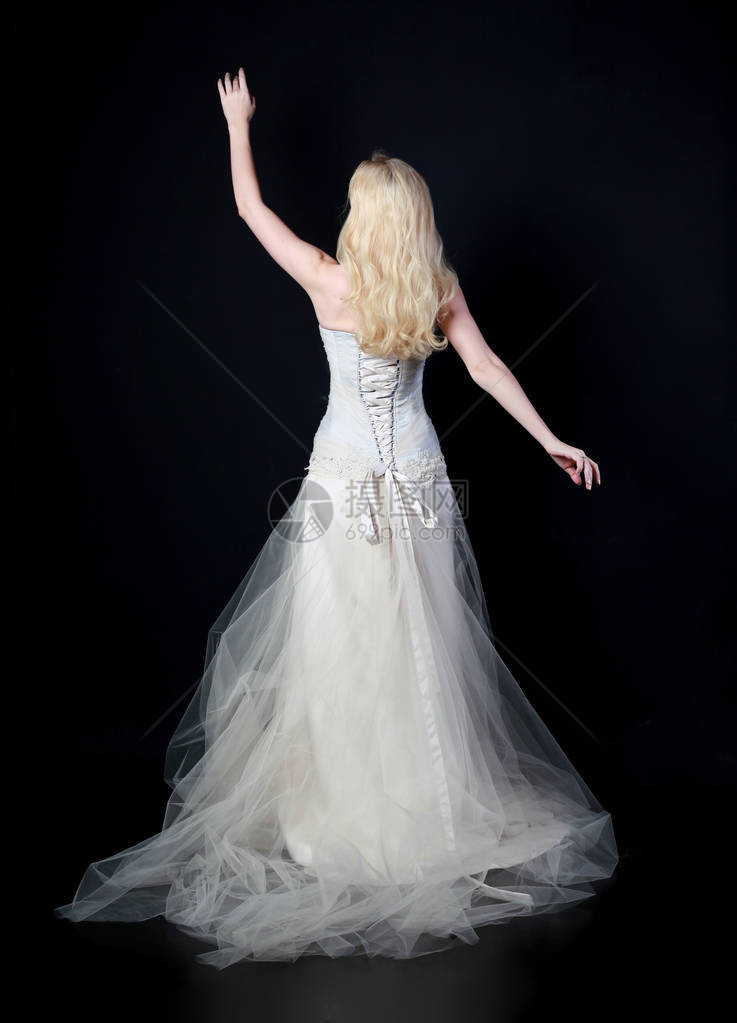 身穿白新娘礼服的模特儿全长肖像站在黑色图片