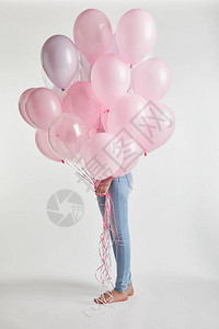 赤脚女孩用白色的粉红色气球遮住脸图片