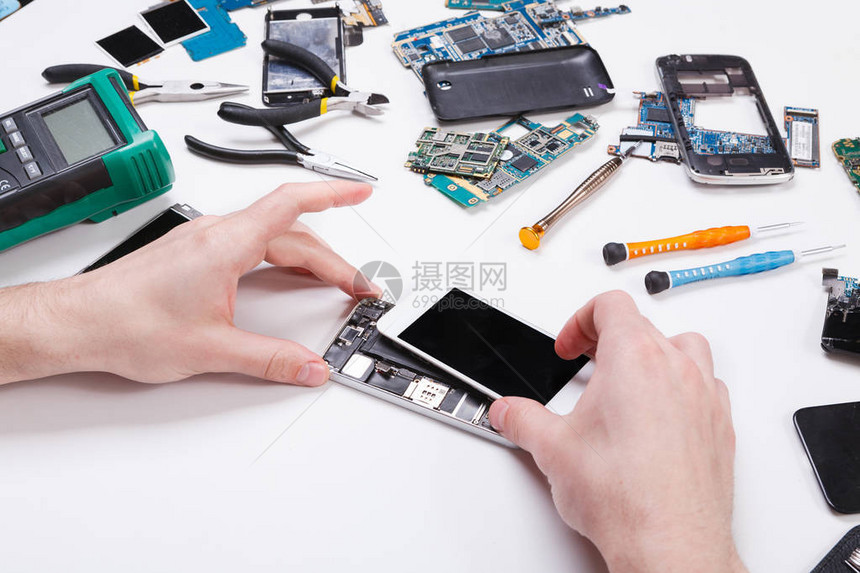 电子维修服务修理工拆卸智能手机进行检查修理坏电话的技术员图片