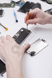 修理工用螺丝刀拆卸智能手机修理坏电话的技术员电子维修服务修理工pov图片