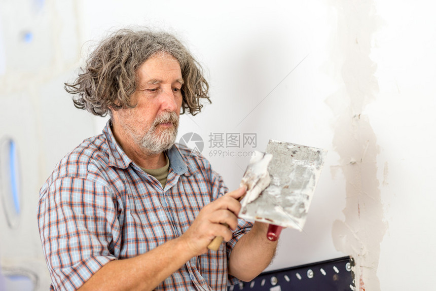中年男建筑商或房主修补墙壁图片