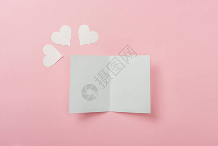 白色空白贺卡和粉红色背景上的纸心背景图片