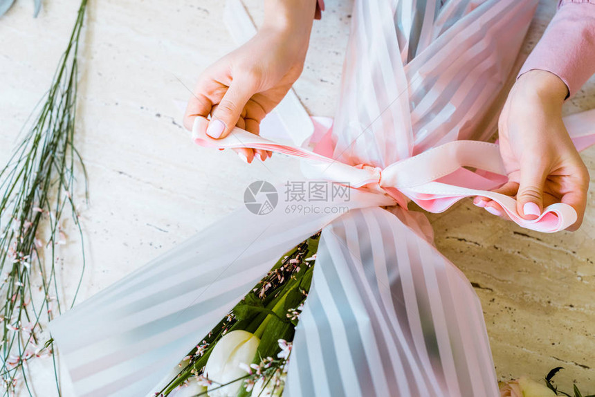 女花店在包装花束时用丝带系蝴蝶结的部分视图图片