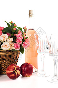 柳条篮中的新鲜天然粉红玫瑰和一瓶玫瑰酒图片