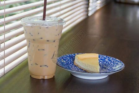 冰咖啡拿铁和白桌上的芝士蛋糕片图片