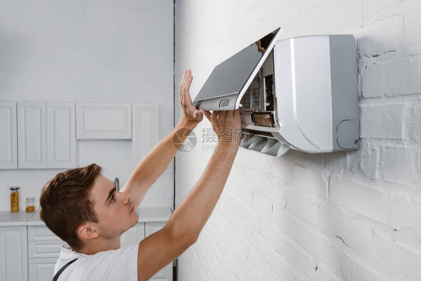 修理工从挂在白砖墙上的空调机上图片
