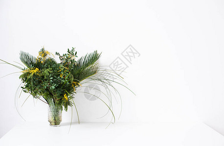 配有绿叶米莫萨花和空白墙的简易花束背景图片