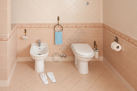 水疗风格的拖鞋位于家庭浴室内的坐浴盆旁图片