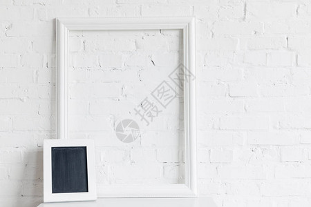 白色砖墙前的空白框和小黑图片