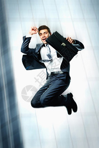 在摩天大楼背景上跳跃公文包的喜乐图片