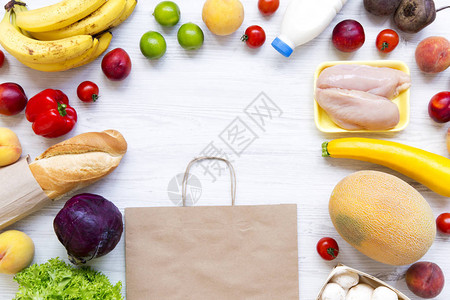 白色木桌上的纸袋套各种杂货烹饪食物背景新鲜食物的平铺顶视图图片