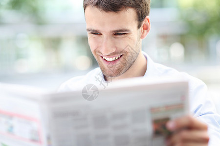 微笑英俊的商人读报纸图片