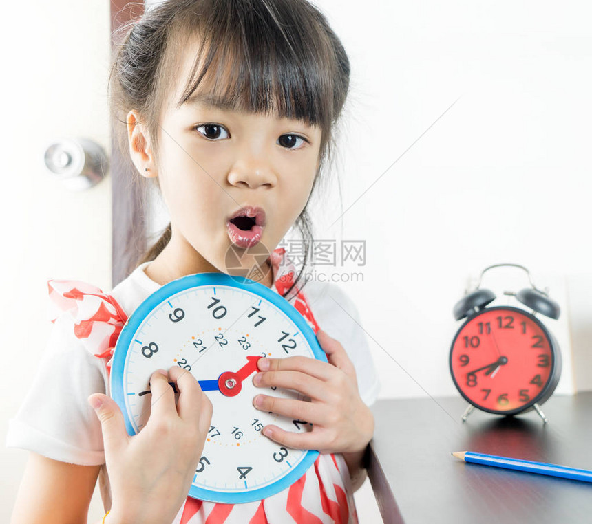 小亚洲女孩拿着玩具钟上图片