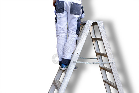 金属梯子上穿着白色工装裤的男子腿背景图片