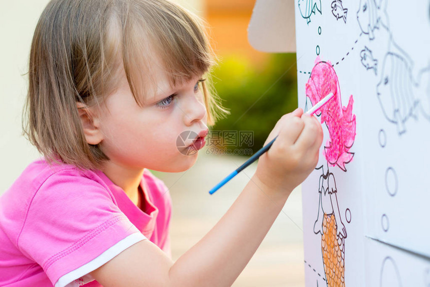 在花园里画纸板屋的小女孩图片