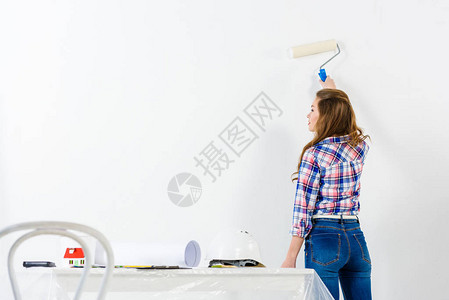 女孩用白漆画墙的后视图图片