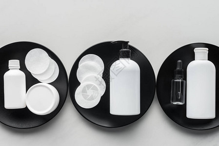 三个黑色板块上三瓶奶油和化妆品垫子的顶部视图片