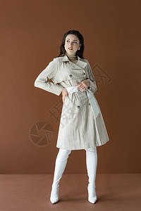 穿着时髦的战壕大衣的流行女在棕图片