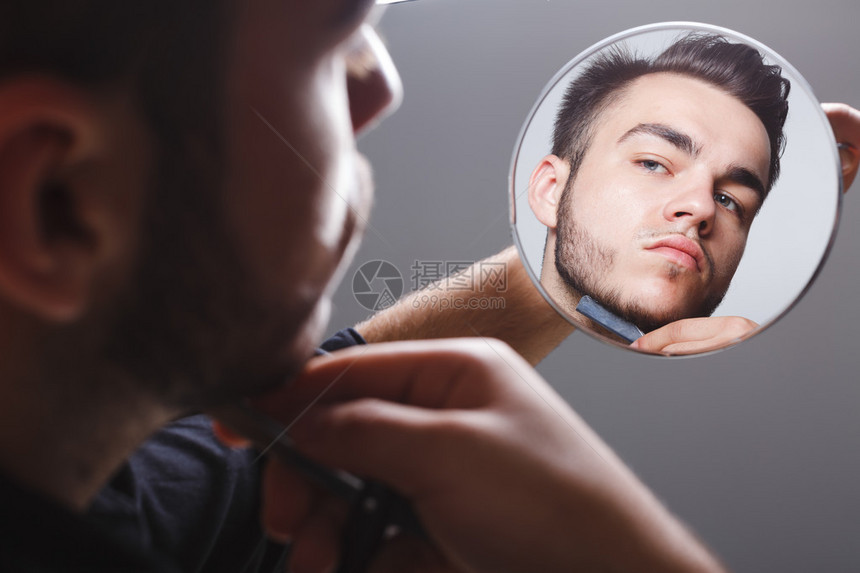 胡子人穿黑色衬衫剃在镜子边白色背景图片